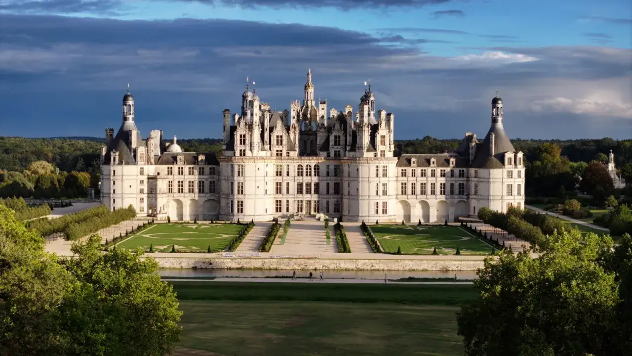 Le majestueux Château de Chambord se dresse, baigné par une lumière douce, avec ses tours et son architecture Renaissance impressionnante.