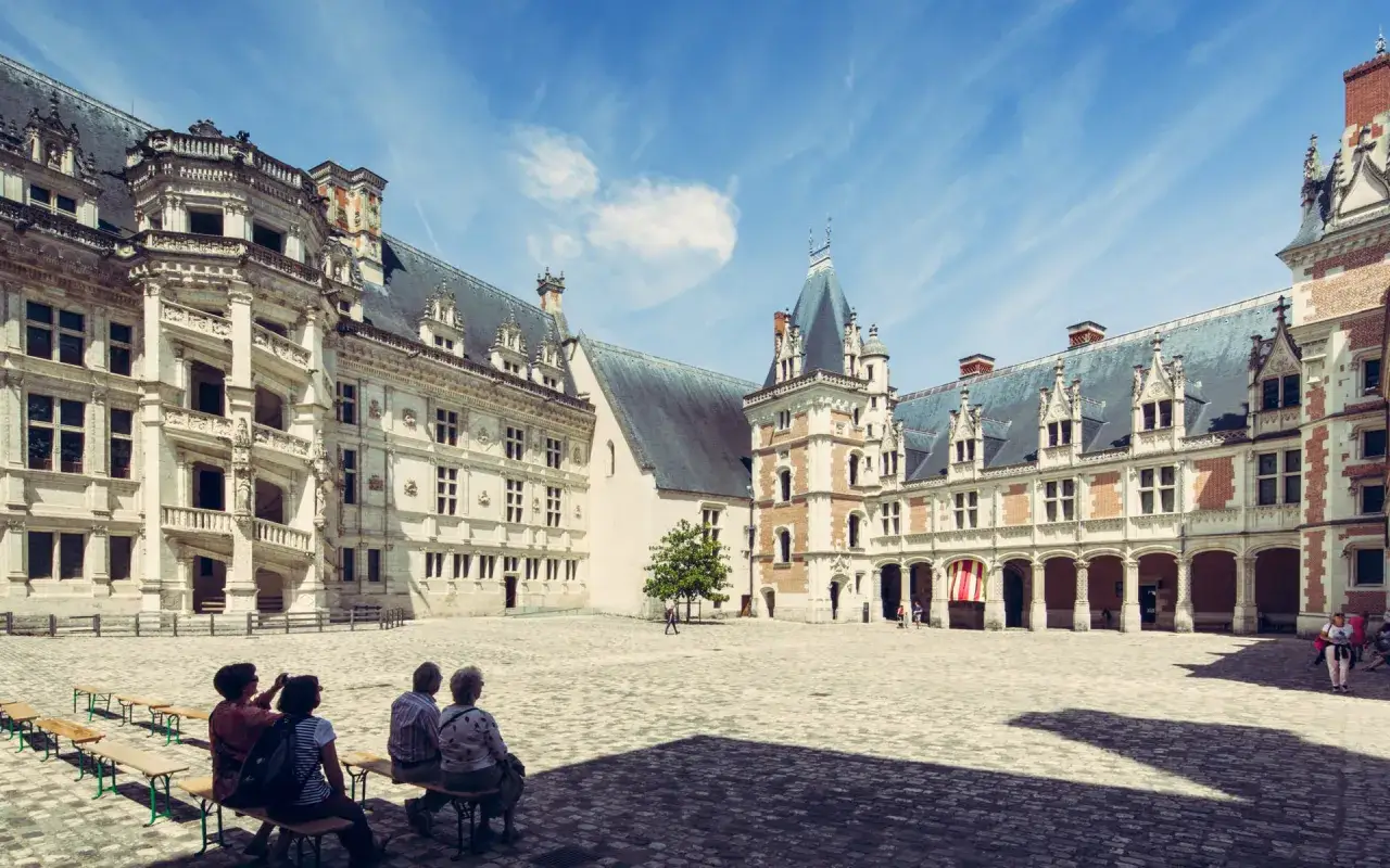 Cour intérieure du château de Blois, avec des visiteurs profitant du temps de visite.