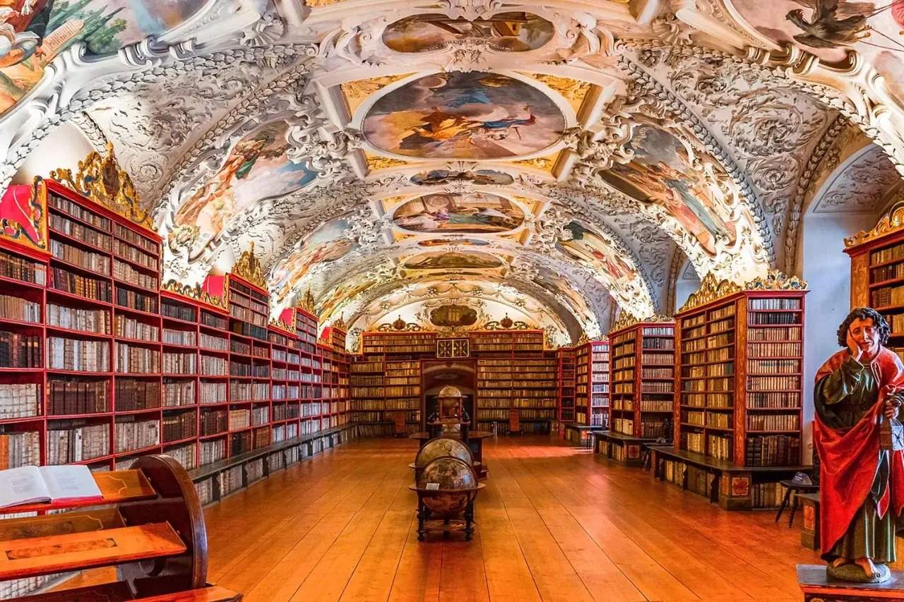 Bibliothèque du monastère de Strahov, avec ses étagères remplies de livres anciens, ses fresques baroques au plafond et ses globes terrestres.