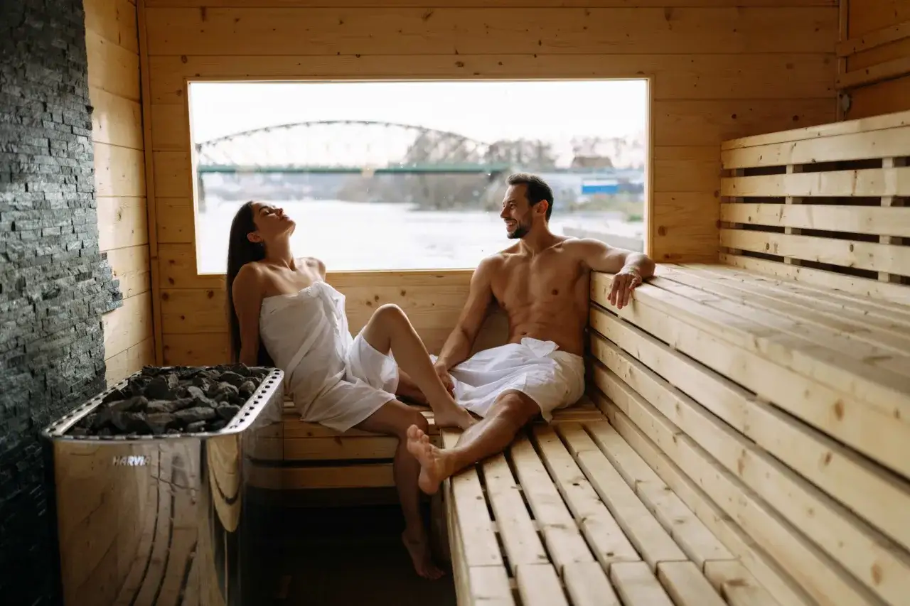 Couple relaxant dans un sauna en bois à Prague, avec vue sur un pont.