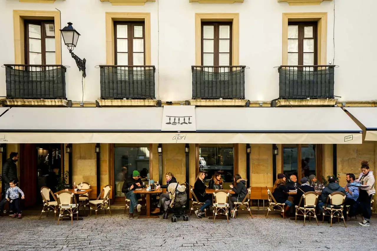 Terrasse animée de restaurants à San Sebastián, où des gens savourent un repas en plein air.