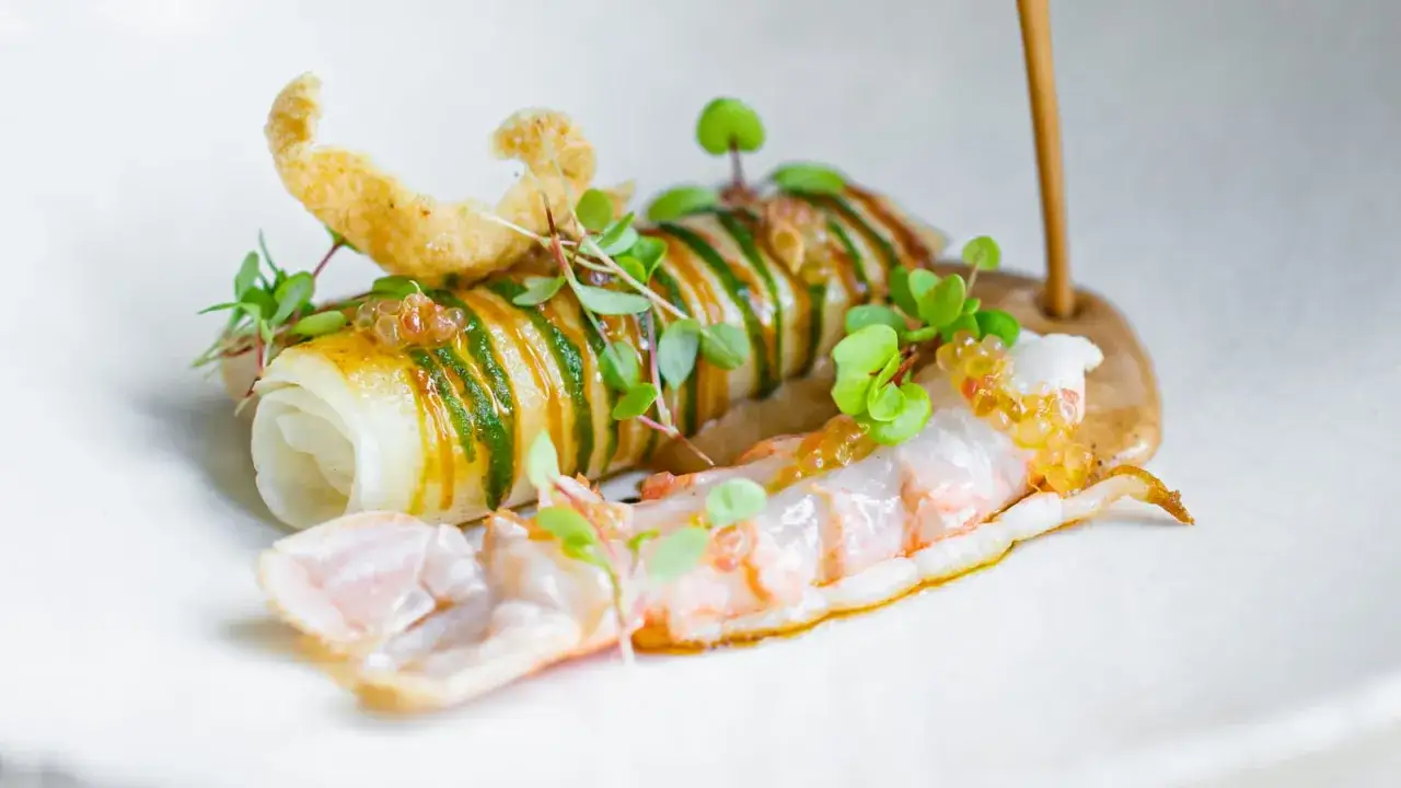 Un plat raffiné d'un restaurant de la Loire : langoustine, rouleau de poisson, croquant et herbes fraîches.