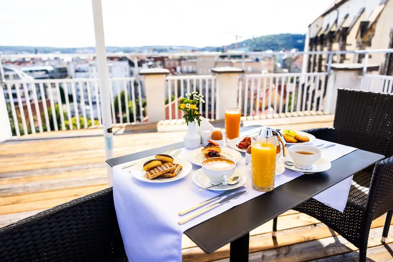 Un délicieux petit déjeuner à Prague sur une terrasse avec vue. Gaufres, pâtisseries, œufs, jus d'orange et café.