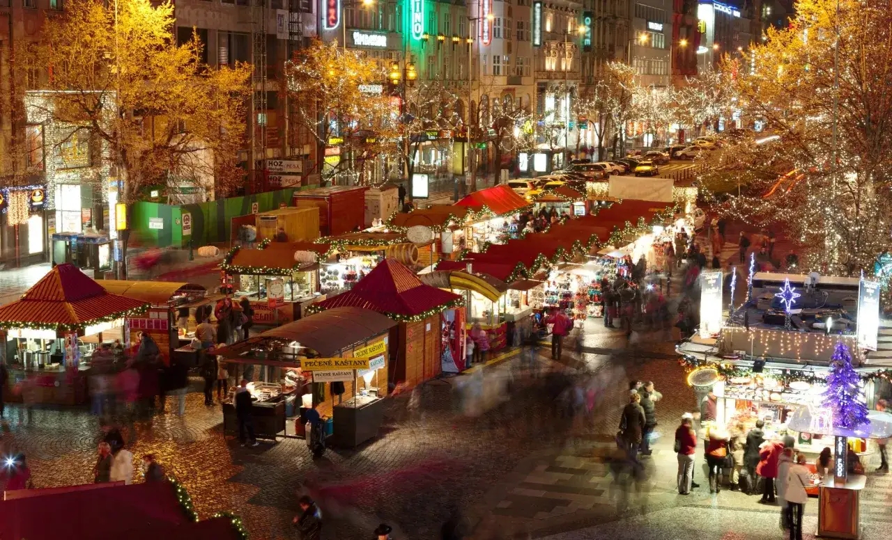 Marché de Noël animé à Prague, avec des stands illuminés et des arbres décorés. L'ambiance festive du quartier rouge de Prague est palpable.