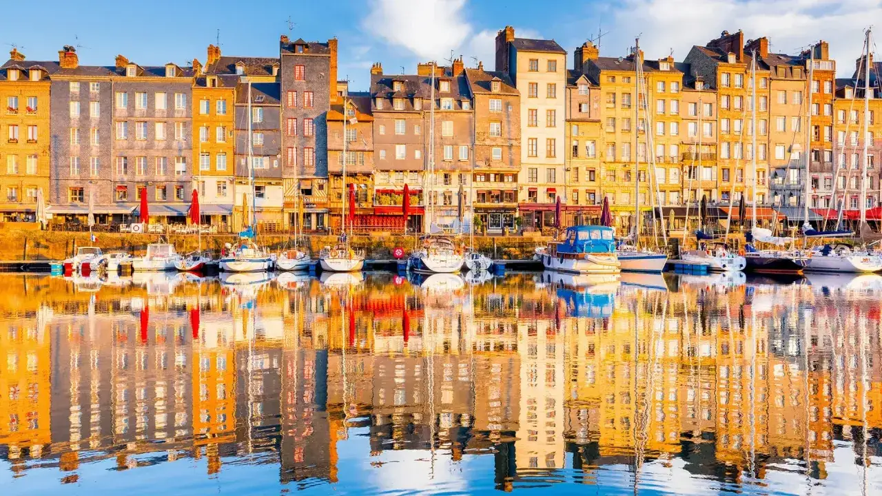 Les façades colorées des maisons de Honfleur se reflètent dans l'eau calme du port, un décor parfait pour un week-end.