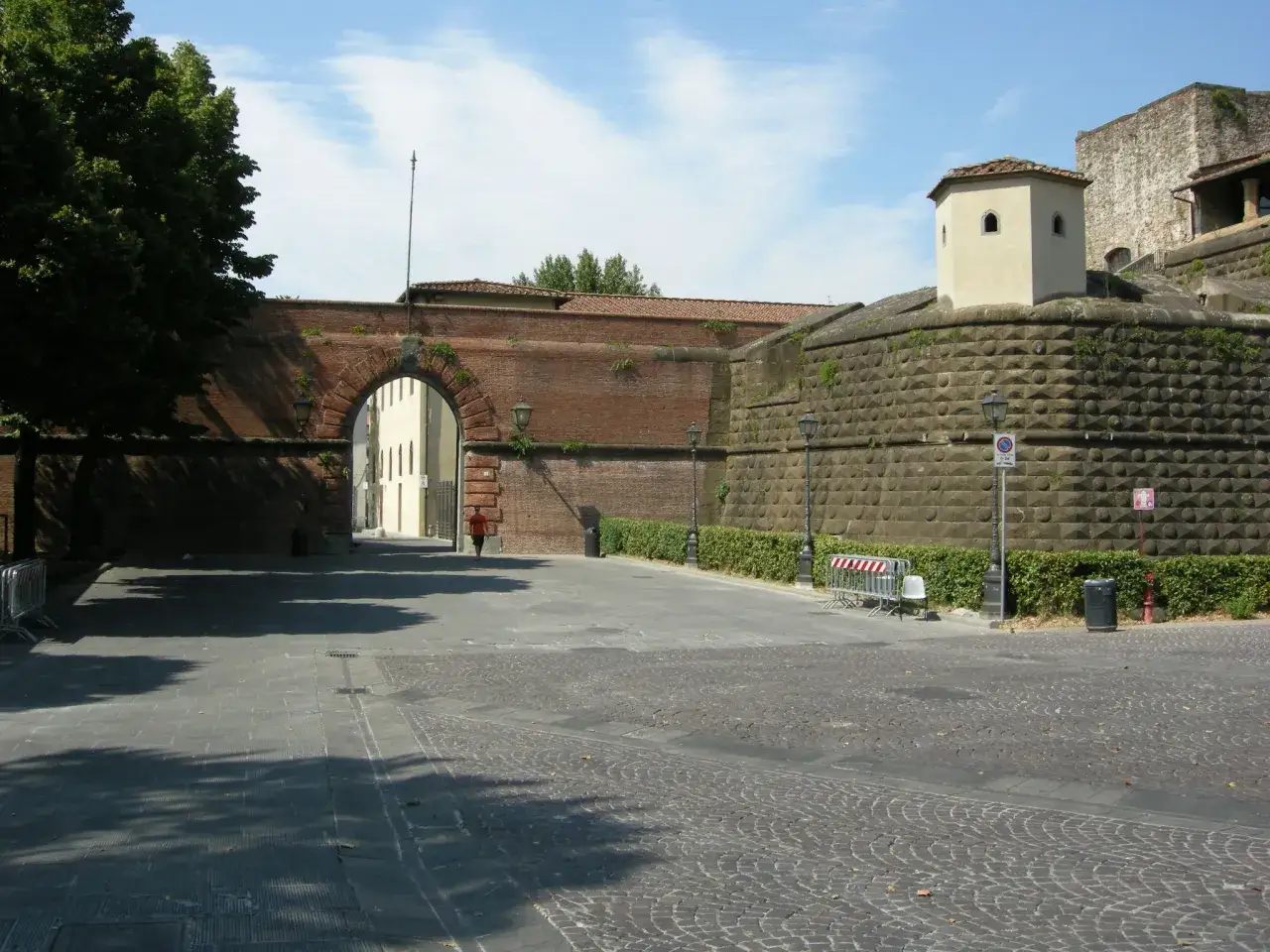 Entrée d'une fortezza da basso avec un mur de briques et une tour de guet.