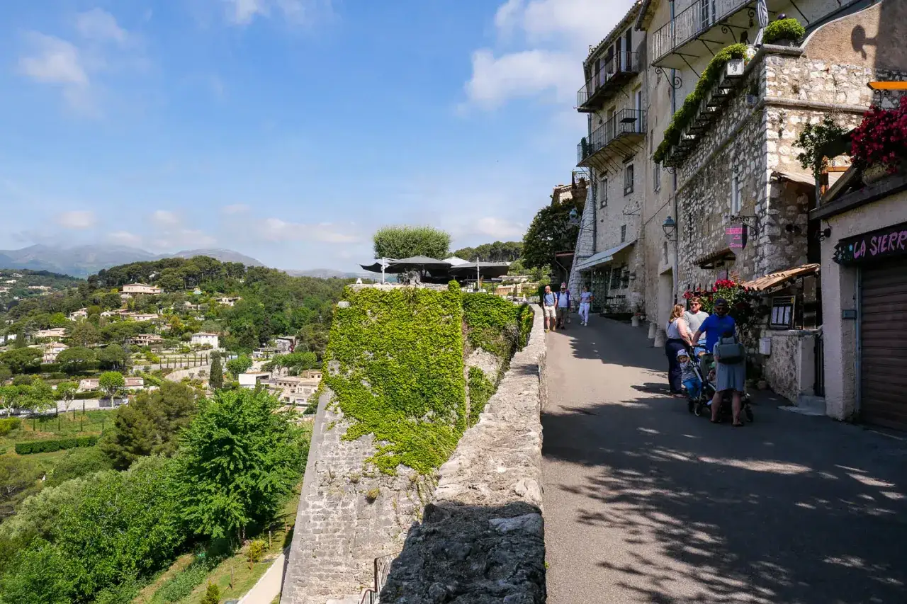 Promenade dans les ruelles de Saint-Paul-de-Vence, avec vue sur les collines verdoyantes et les maisons de pierre.