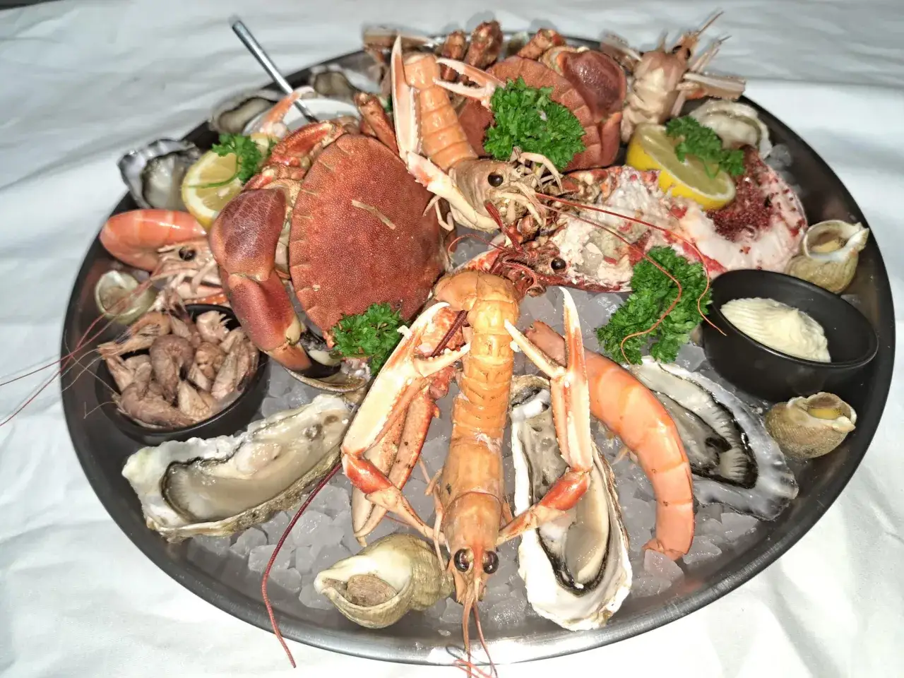 Plateau de fruits de mer à Honfleur : homard, langoustines, crevettes, huîtres et bulots sur glace. Un délice pour savoir où manger à Honfleur.