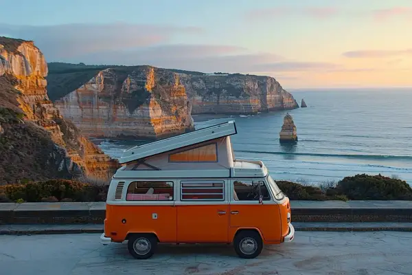 Un camping-car orange avec toit relevable sur une falaise portugaise. Idéal pour un budget pour aller au Portugal en camping-car.