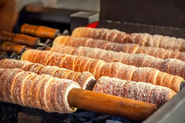 Trdelník, un délicieux dessert tchèque, cuit sur des broches en bois, saupoudré de sucre.