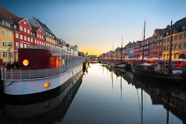 Canal de Nyhavn à Copenhague au coucher du soleil, avec des maisons colorées et des bateaux. Parfait pour un week-end copenhague.
