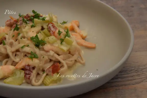 Pâtes à la toscane crémeuses avec crevettes, tomates séchées et céleri, garnies de persil frais. Un délice pour les gourmands.