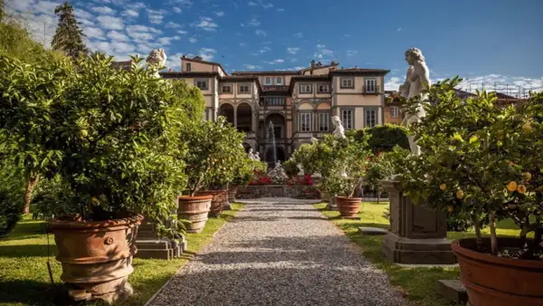 Palazzo Pfanner et son jardin à Lucca, avec des arbres en pot, des statues et une fontaine.