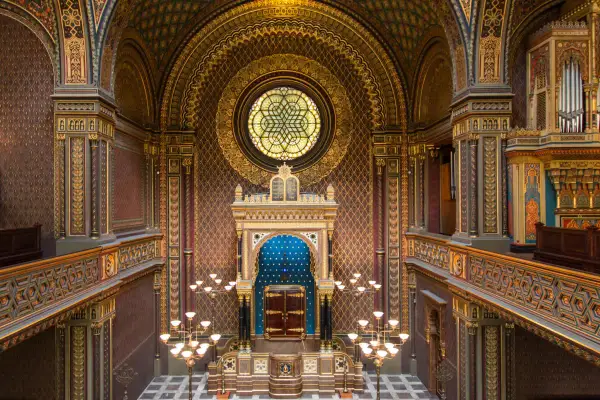 Intérieur orné de la synagogue espagnole de Prague, avec un vitrail circulaire, un Aron Kodesh bleu et des lustres dorés.