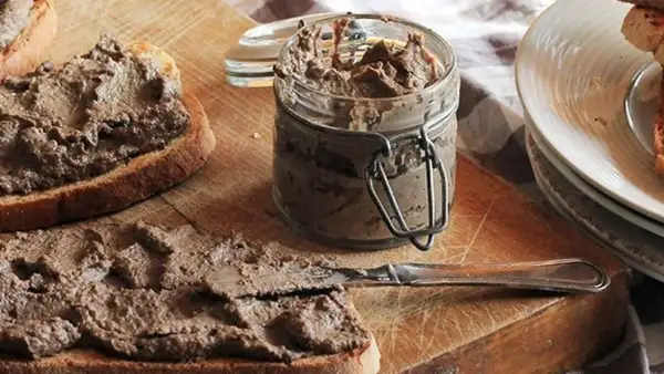 Des toasts tartinés de pâté, prêts à déguster. Un pot de crostini toscani et une assiette de crostini empilés complètent cette scène gourmande.