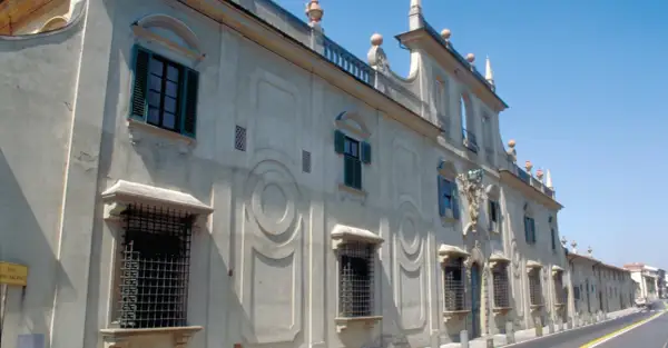 Façade d'une villa à Sesto Fiorentino, avec des fenêtres à volets verts et des ornements circulaires sur le mur.