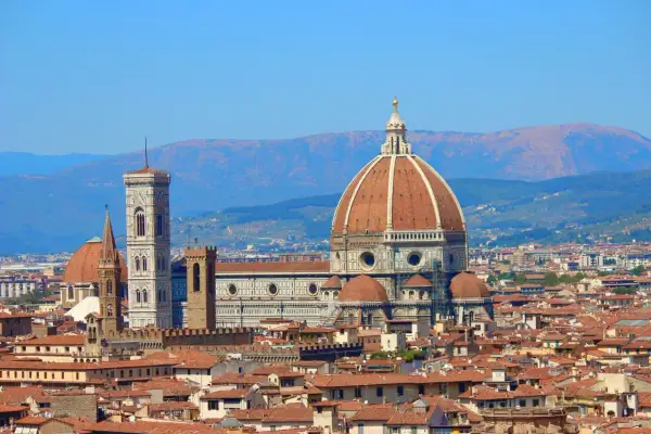 La célèbre coupole de Florence domine la ville, avec son campanile et ses toits de tuiles rouges sous un ciel bleu.