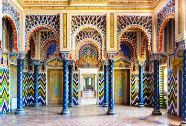 Intérieur du Castello di Sammezzano, une salle aux arcs mauresques, colonnes bleues et motifs géométriques colorés.