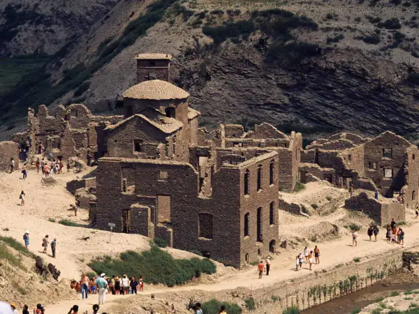 Ruines de pierre du lago di vagli, un village fantôme envahi par la végétation, avec des visiteurs explorant les vestiges.