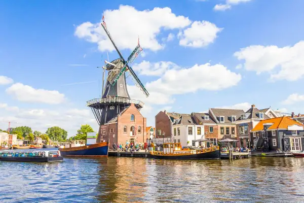 Un moulin à vent historique domine un canal bordé de maisons pittoresques. Une idée de que faire aux Pays-Bas : flâner le long de l'eau.