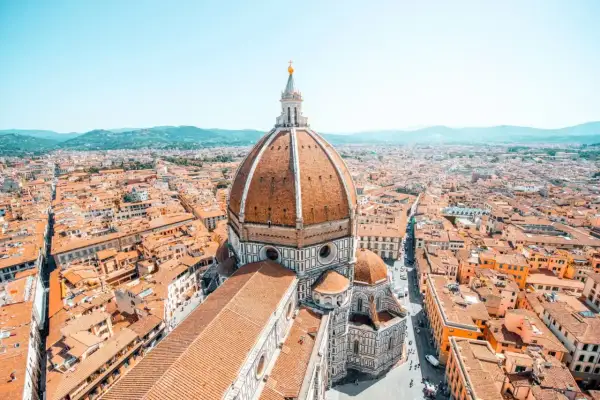 Vue aérienne de Florence, avec le dôme de Brunelleschi dominant la ville. Les toits de tuiles orangées s'étendent à perte de vue.