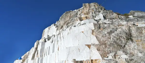 Carrières de marbre blanc à Carrare, Italie, sous un ciel bleu intense. Les blocs taillés révèlent la beauté brute de la roche.