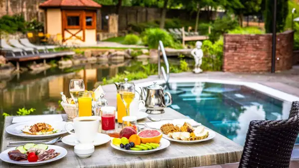 Petit-déjeuner copieux au domaine Moulin Ensisheim, avec vue sur la piscine et le jardin.