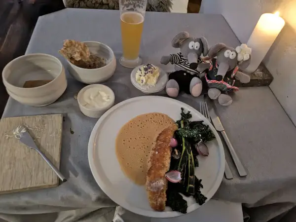 Un dîner romantique dans un restaurant de Copenhague pas cher. Deux souris en peluche observent un plat de poisson, des légumes et une mousse.